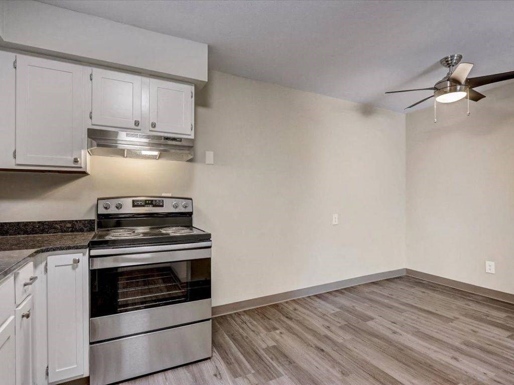 an empty kitchen with a stove and a ceiling fan