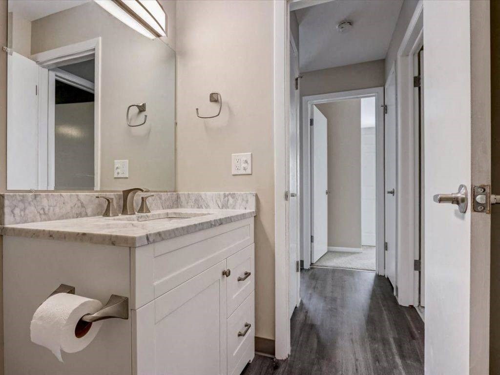 a bathroom with a sink and a mirror and a hallway