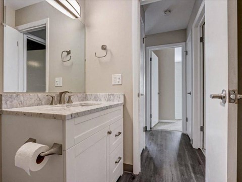 a bathroom with a sink and a mirror and a hallway