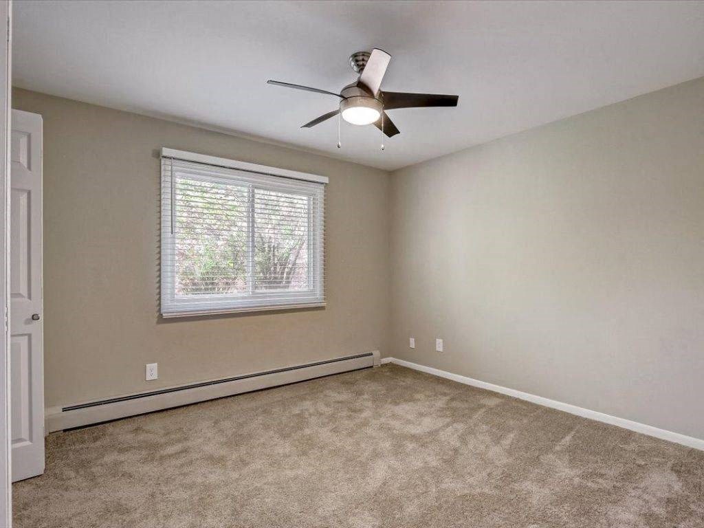 an empty living room with a ceiling fan and a window