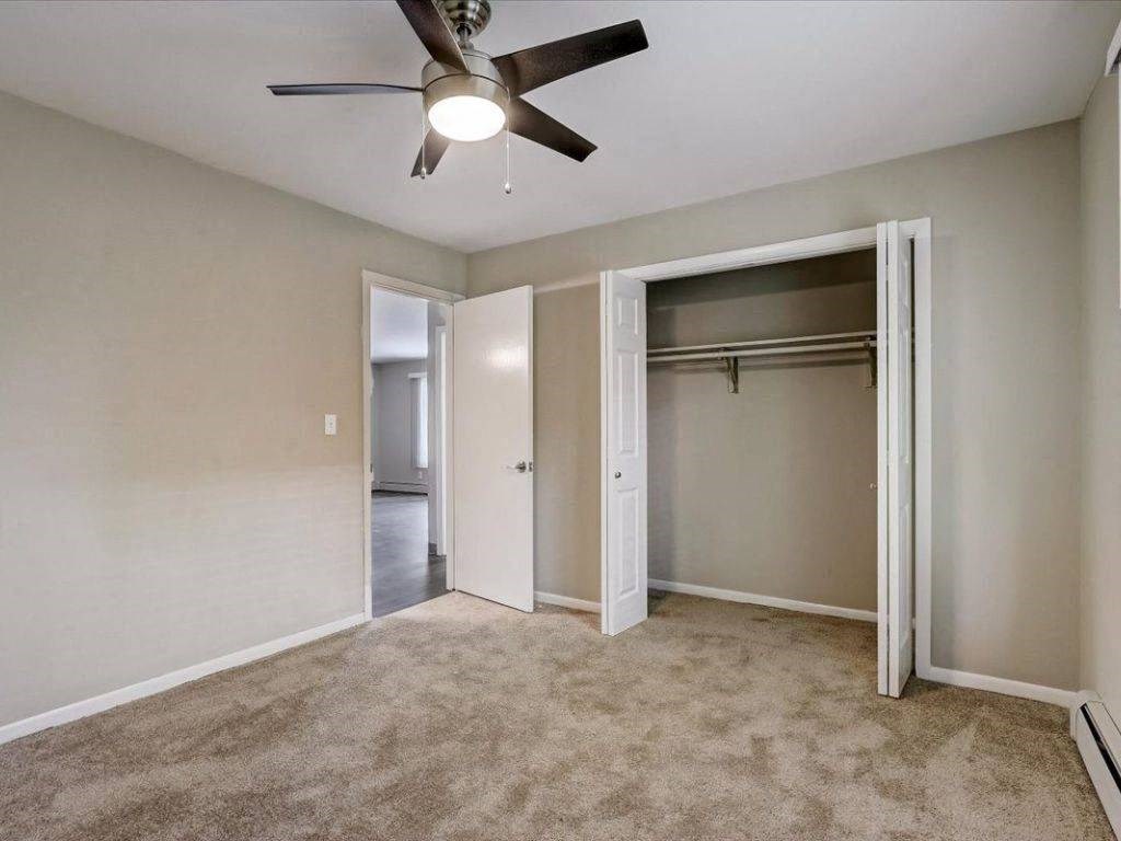 an empty bedroom with a ceiling fan and a closet
