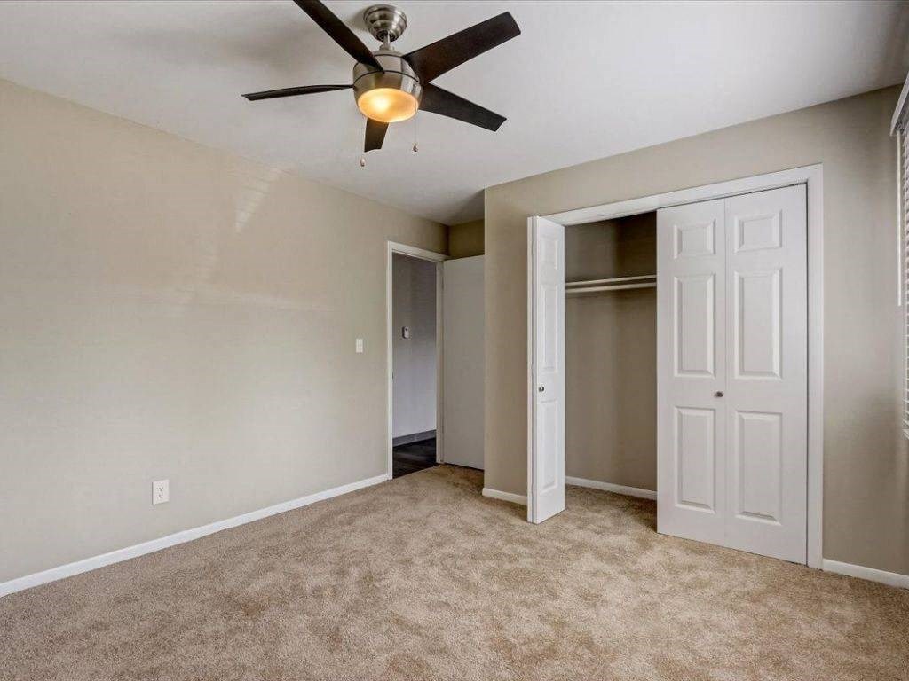 an empty living room with a ceiling fan and a closet