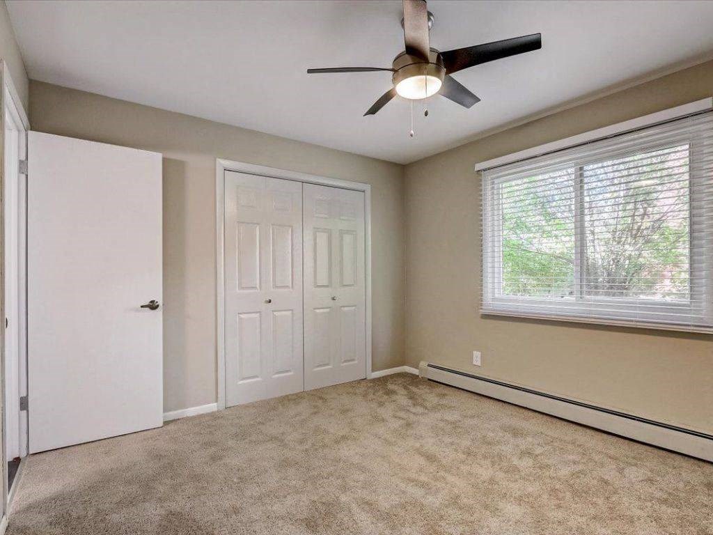 an empty bedroom with a ceiling fan and a window