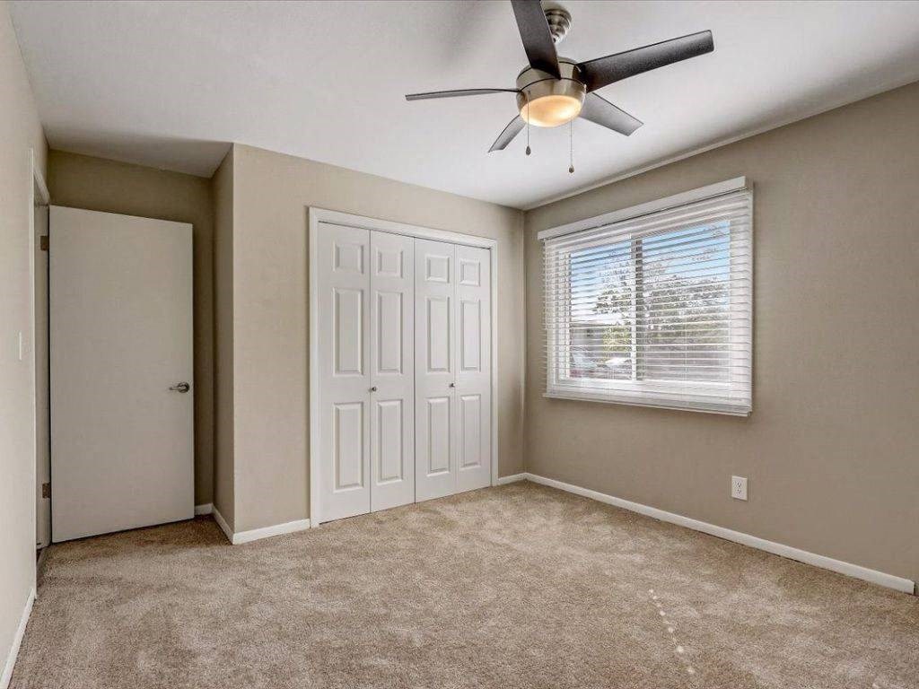 an empty bedroom with a ceiling fan and a window