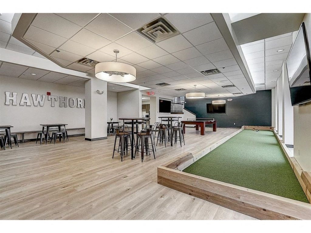 a game room with a green carpet and tables and chairs