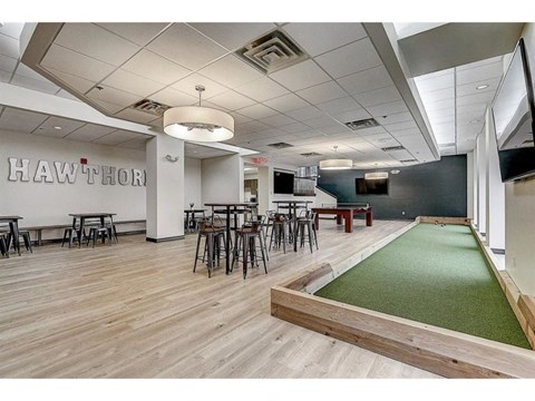a game room with a green carpet and tables and chairs