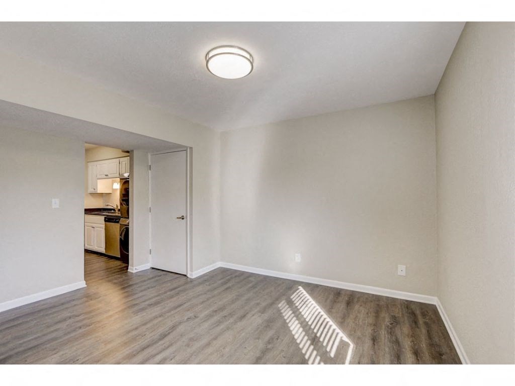 a spacious living room with wood flooring and a door to the kitchen