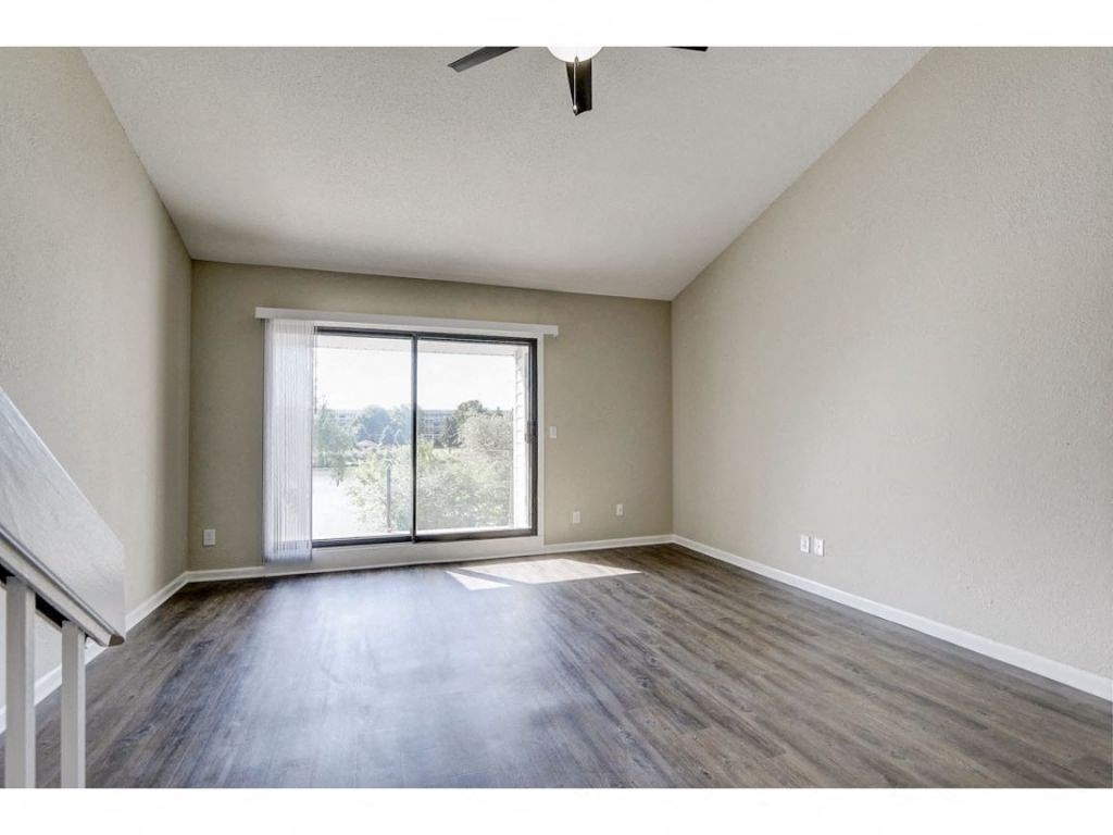 an empty living room with a large window and wood floors
