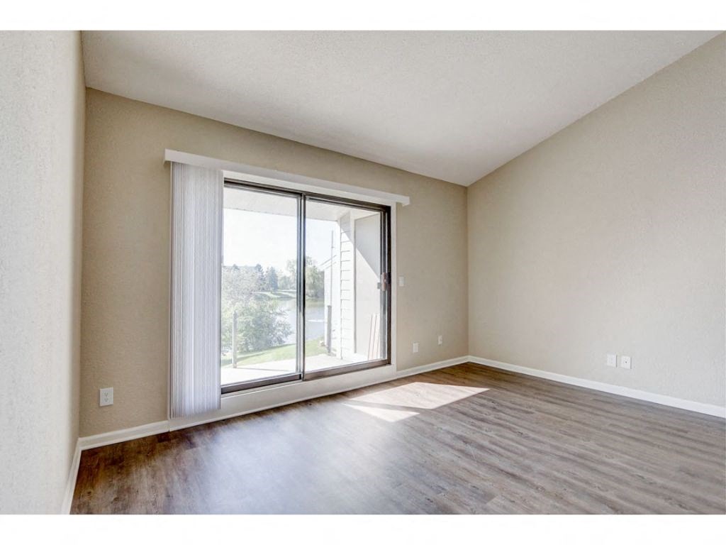 an empty living room with a large window and wood floors