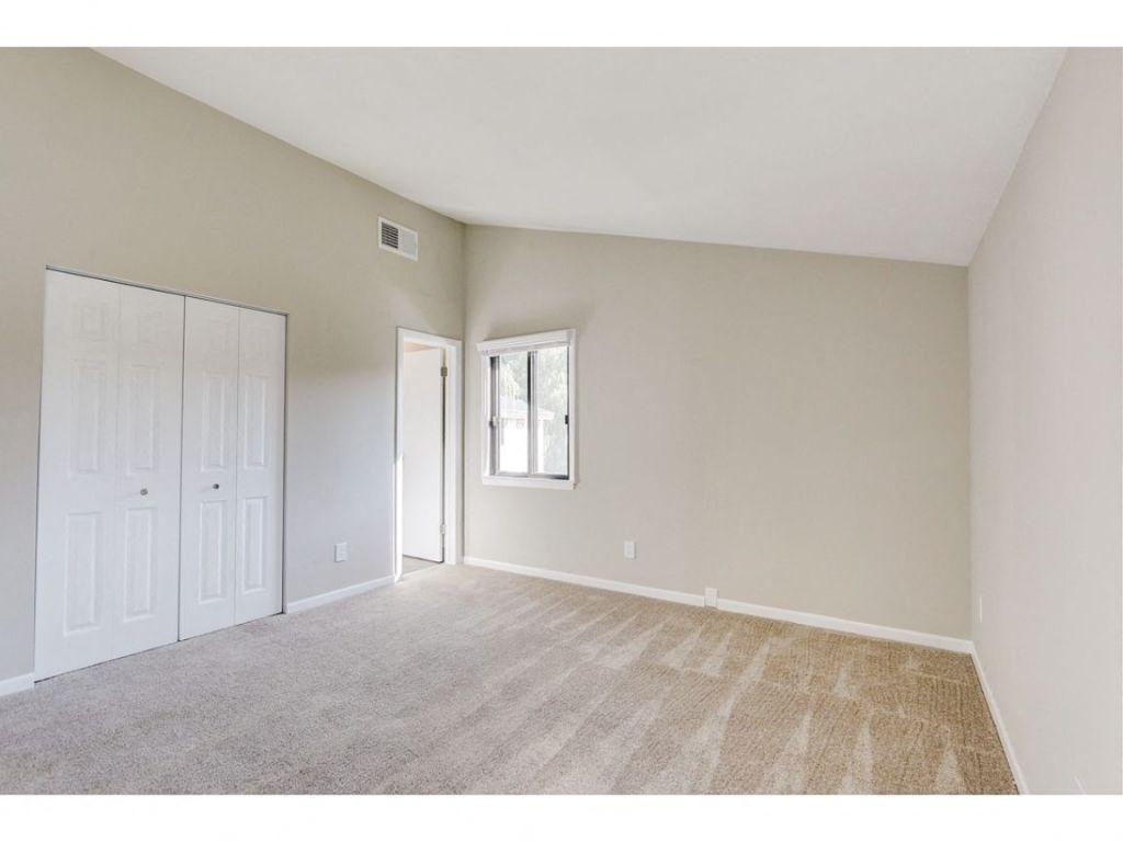 an empty living room with carpet and a door to a closet