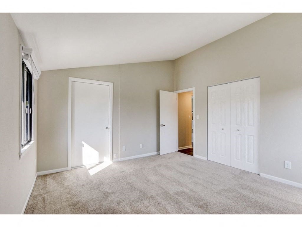 an empty living room with white doors and carpet