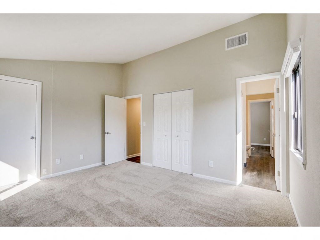 an empty living room with white walls and a door to a hallway
