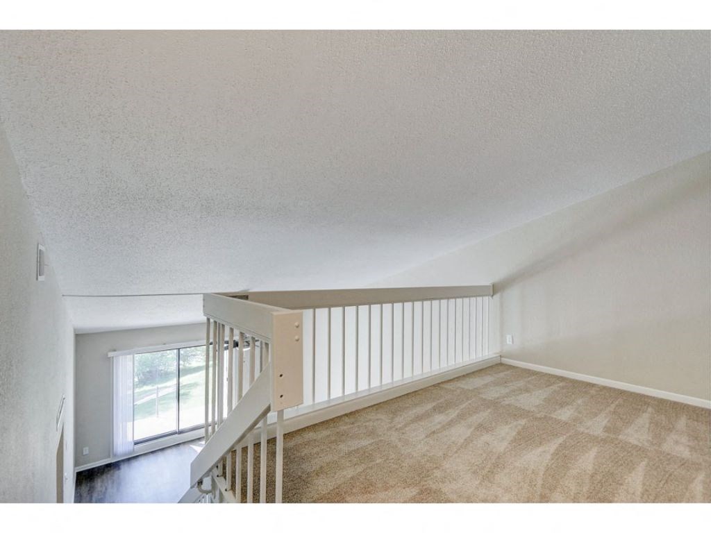an upstairs living room with a staircase and a window