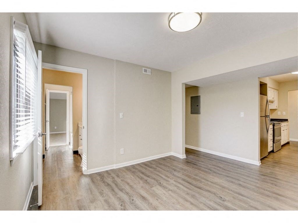 a spacious living room with wood flooring and an open kitchen