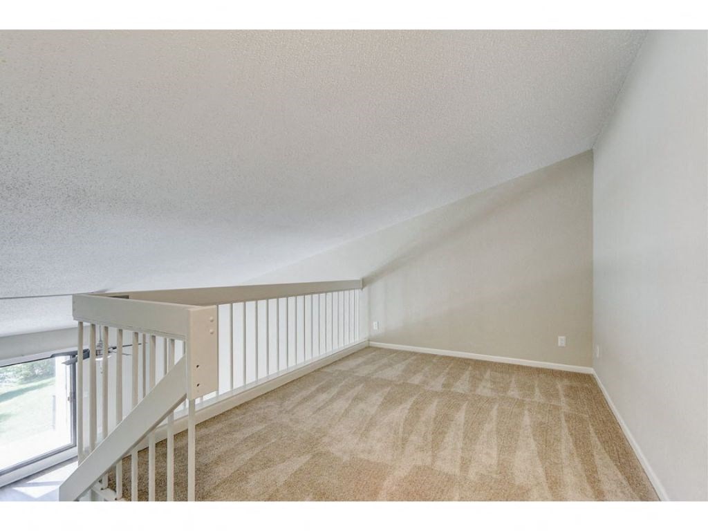 an upstairs loft with carpeted stairs and a window
