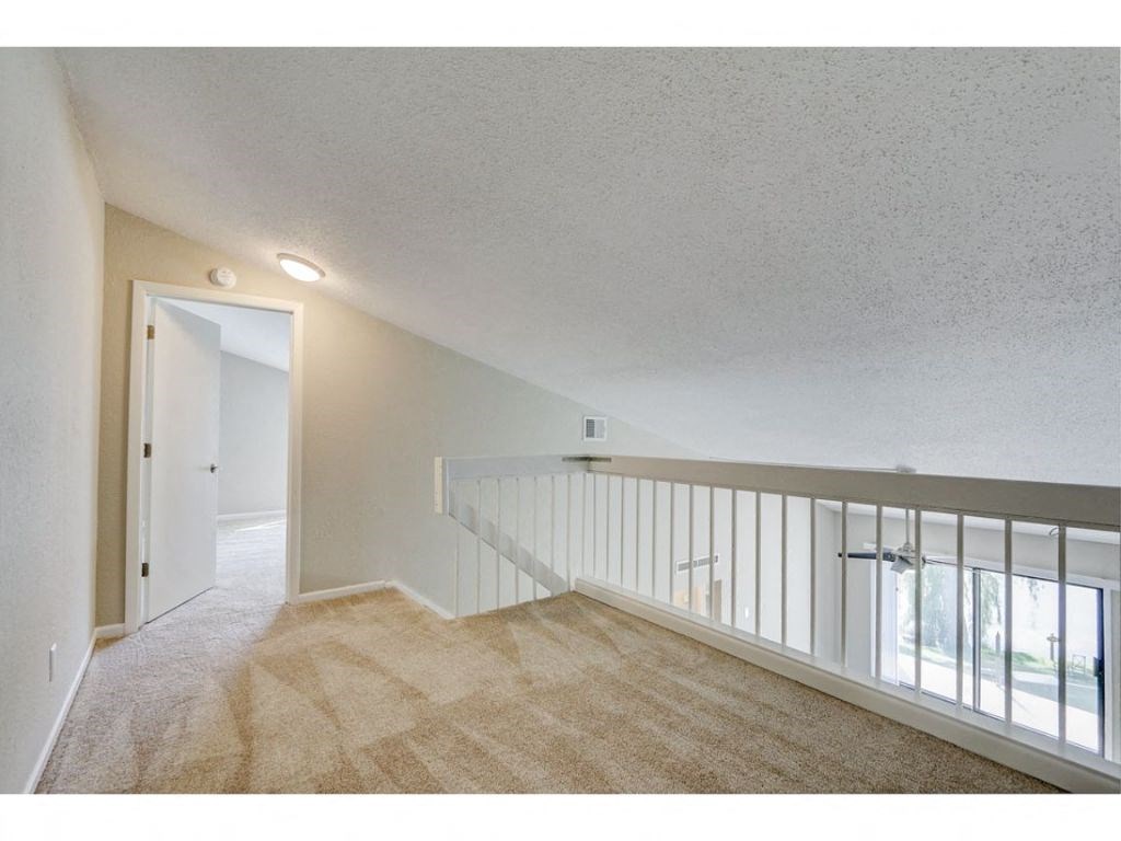 an upstairs loft with a door to a hallway and a staircase