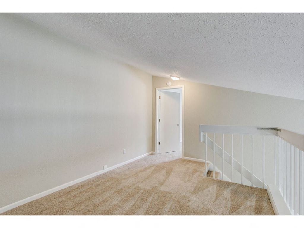 a living room with carpeted stairs and a door to a bedroom