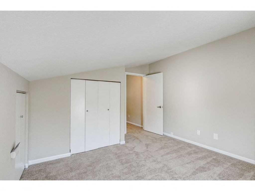an empty living room with white closets and carpeting