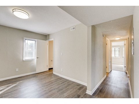 a spacious living room with wood floors and a door to a hallway