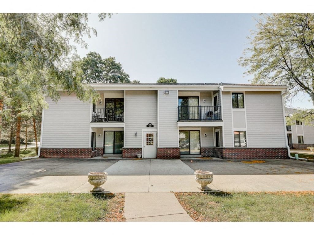 the front of a white house with a driveway and trees