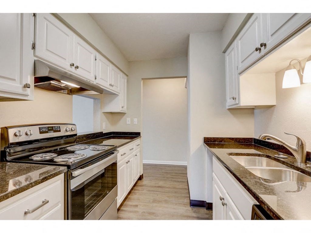 a kitchen with white cabinets and a stove and a sink