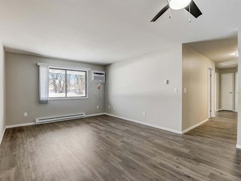 an empty living room with wood floors and a window