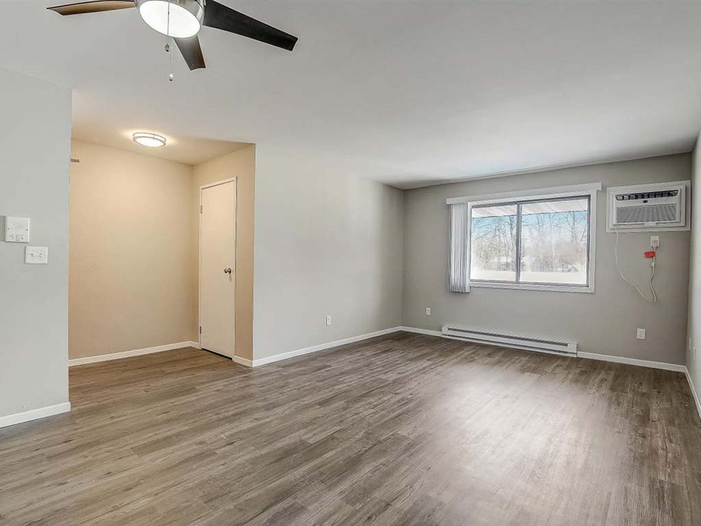 an empty living room with wood floors and a window
