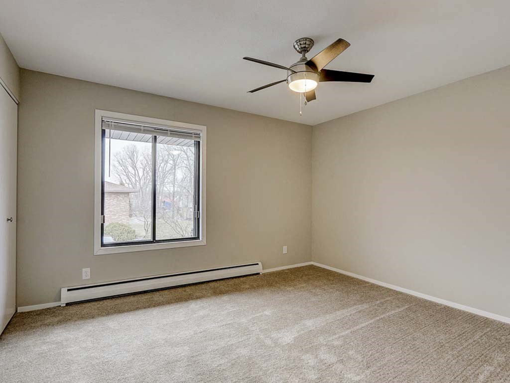 an empty living room with a ceiling fan and a window