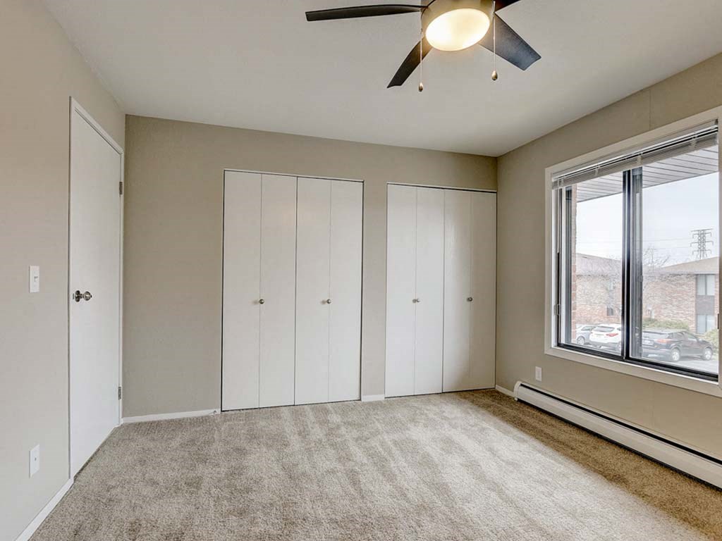 an empty living room with a ceiling fan and a window