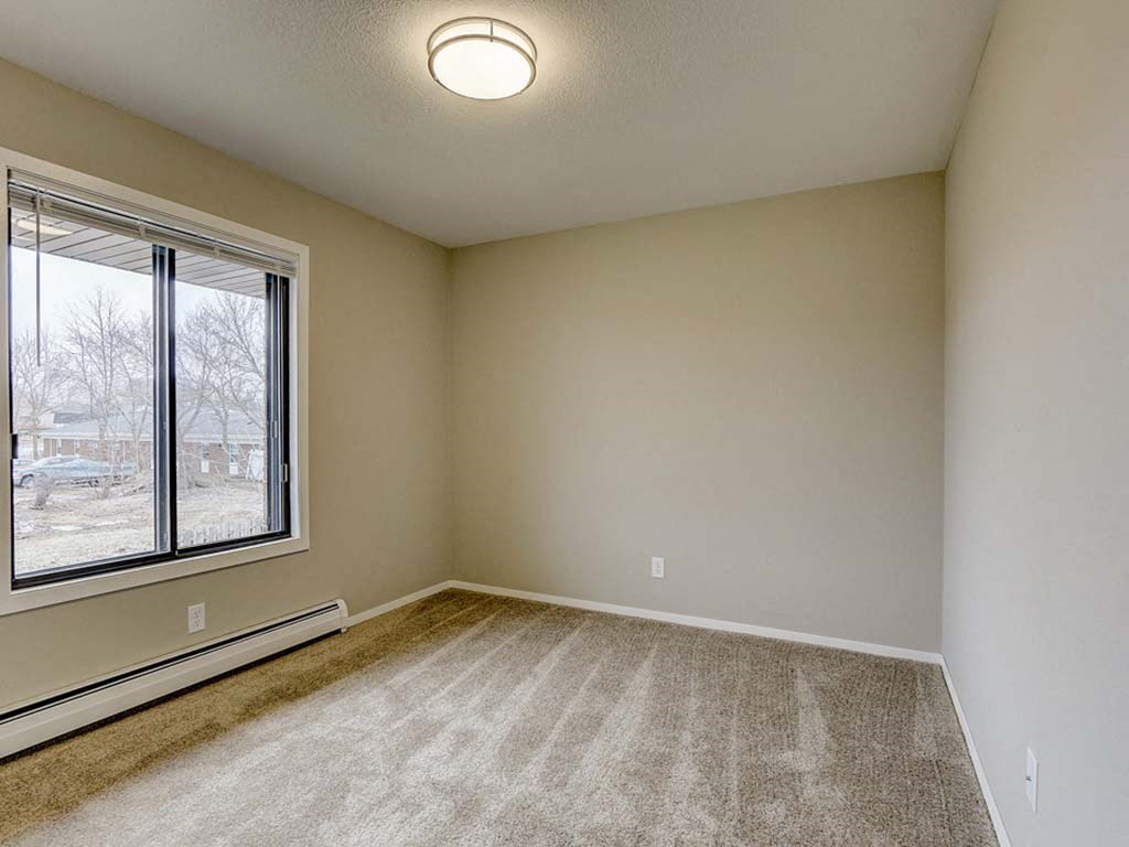 an empty living room with a large window and carpet