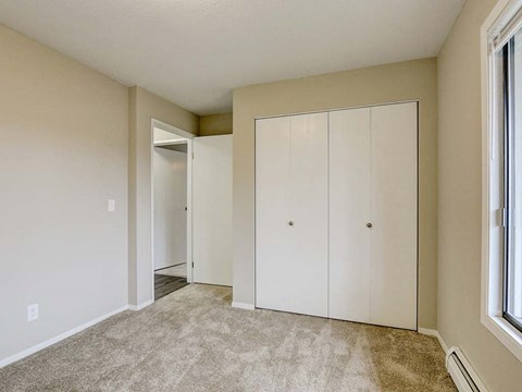 A room with a carpeted floor and a large white wardrobe.