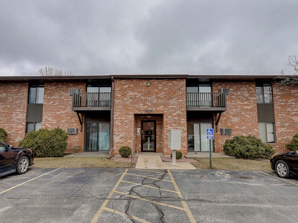 the front of a brick building with a parking lot