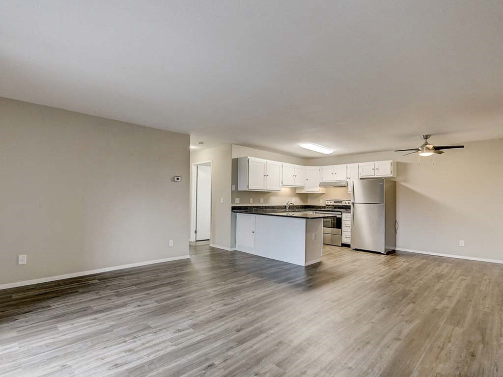 an empty living room and kitchen with wood flooring