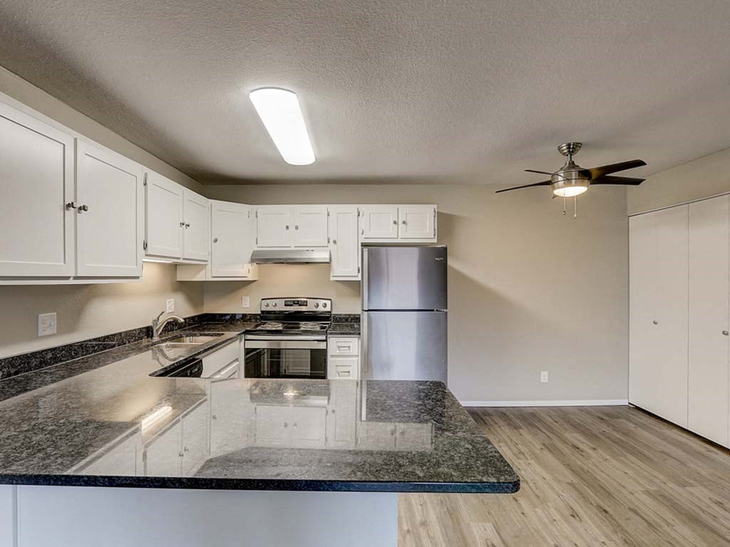 a kitchen with granite counter tops and a stainless steel refrigerator