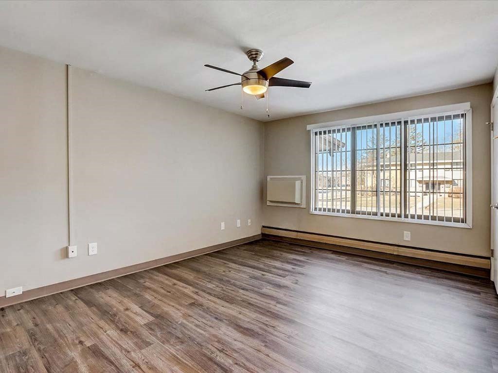 an empty living room with a ceiling fan and a window