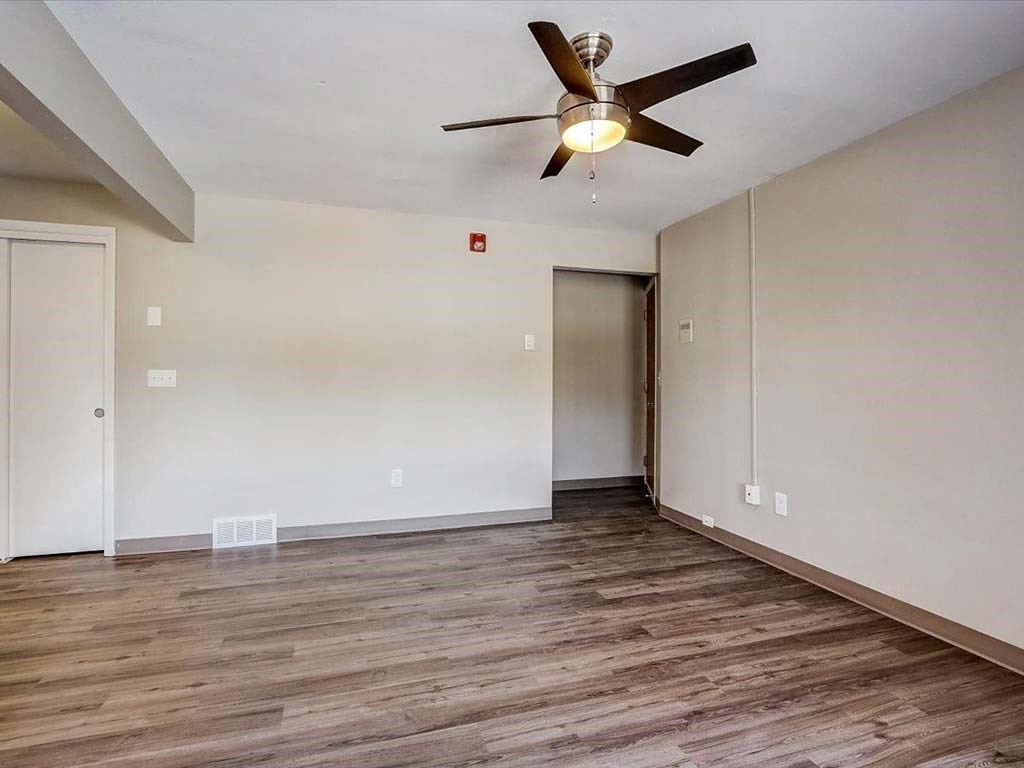an empty living room with a ceiling fan and white walls