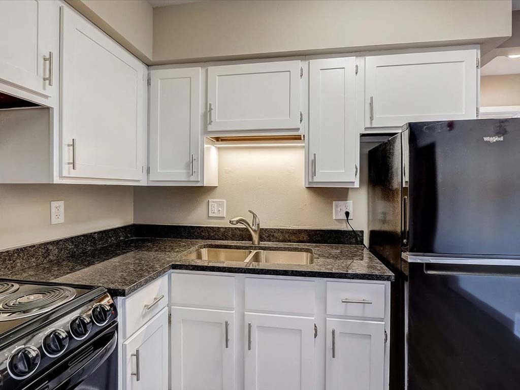 a kitchen with white cabinets and a sink and a refrigerator