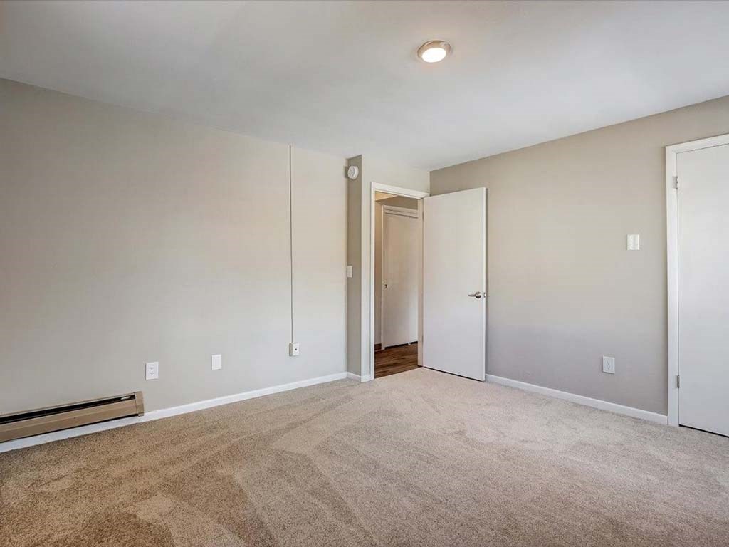 an empty living room with white walls and carpet
