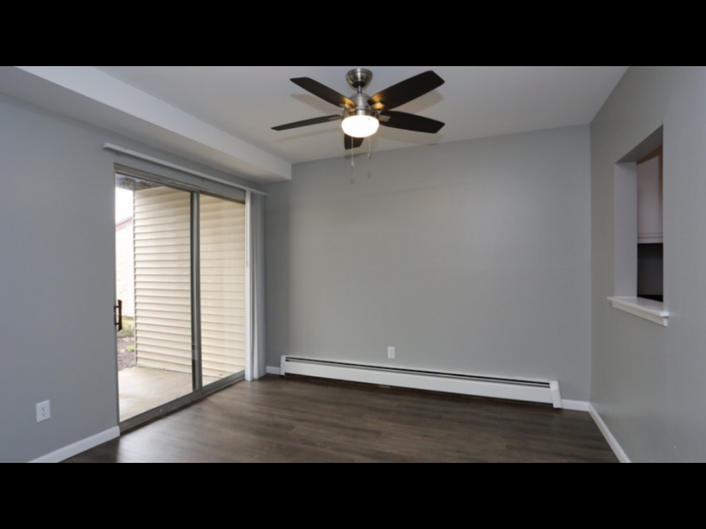 a living room with a ceiling fan and a sliding glass door