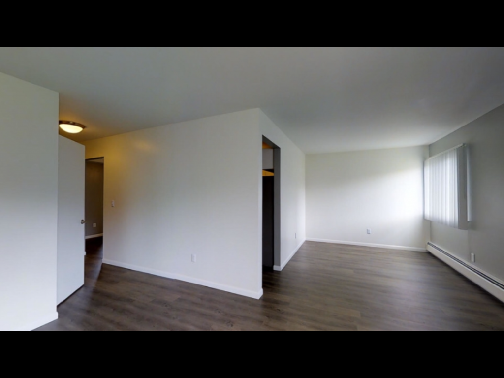 an empty living room with white walls and wood floors