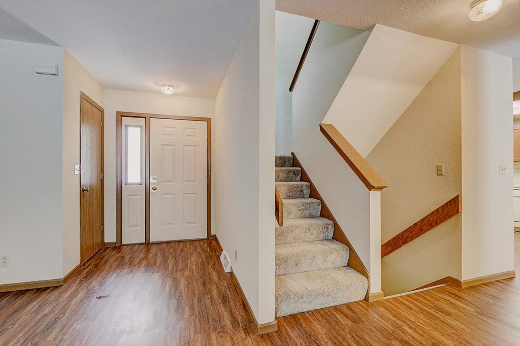 the entryway of a house with stairs and a white door