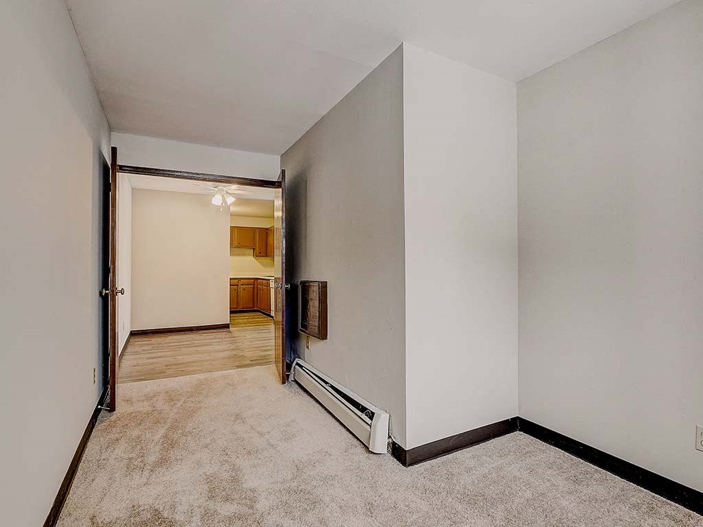 an empty living room with a door to a kitchen