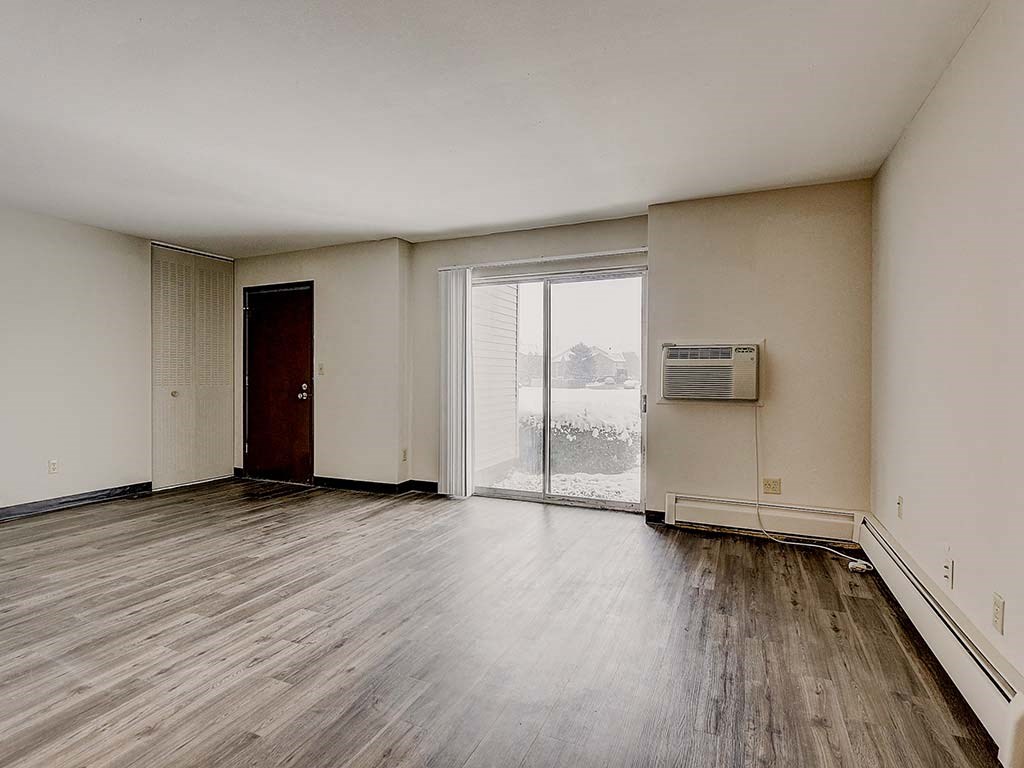 an empty living room with wood floors and a window
