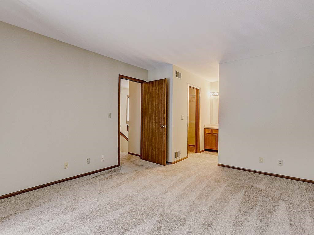 an empty living room with a door to a bathroom