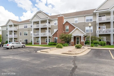 A car is parked in front of a multi-story apartment building.