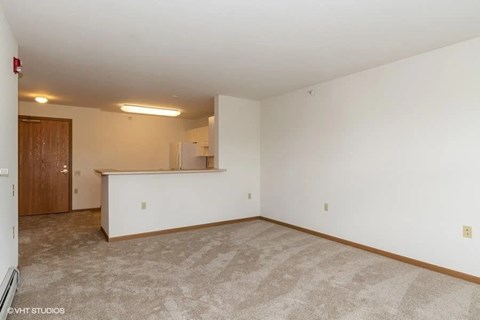 A spacious room with a carpeted floor and a white wall.