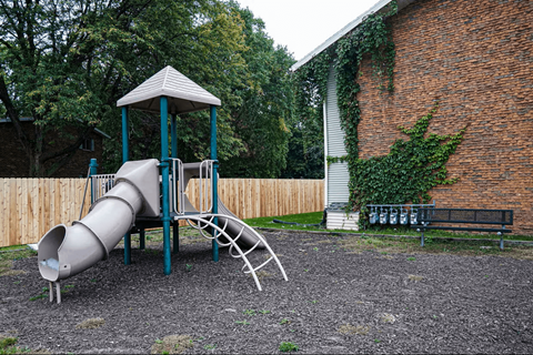 A playground with a slide and a wooden fence.