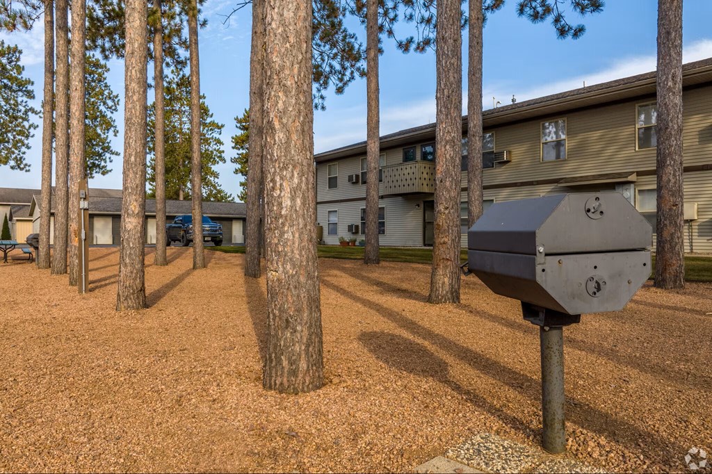 A mailbox is in the foreground of a residential area with houses and trees in the background.