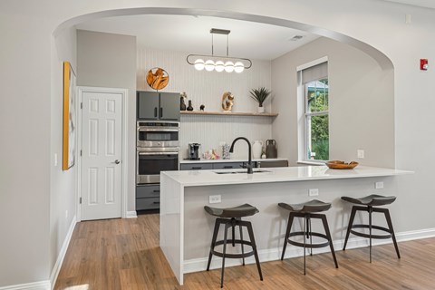 A kitchen with a white counter top and bar stools.