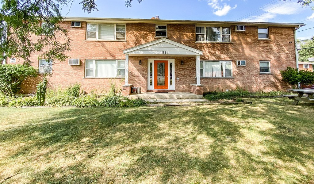 the front of a brick house with a red door